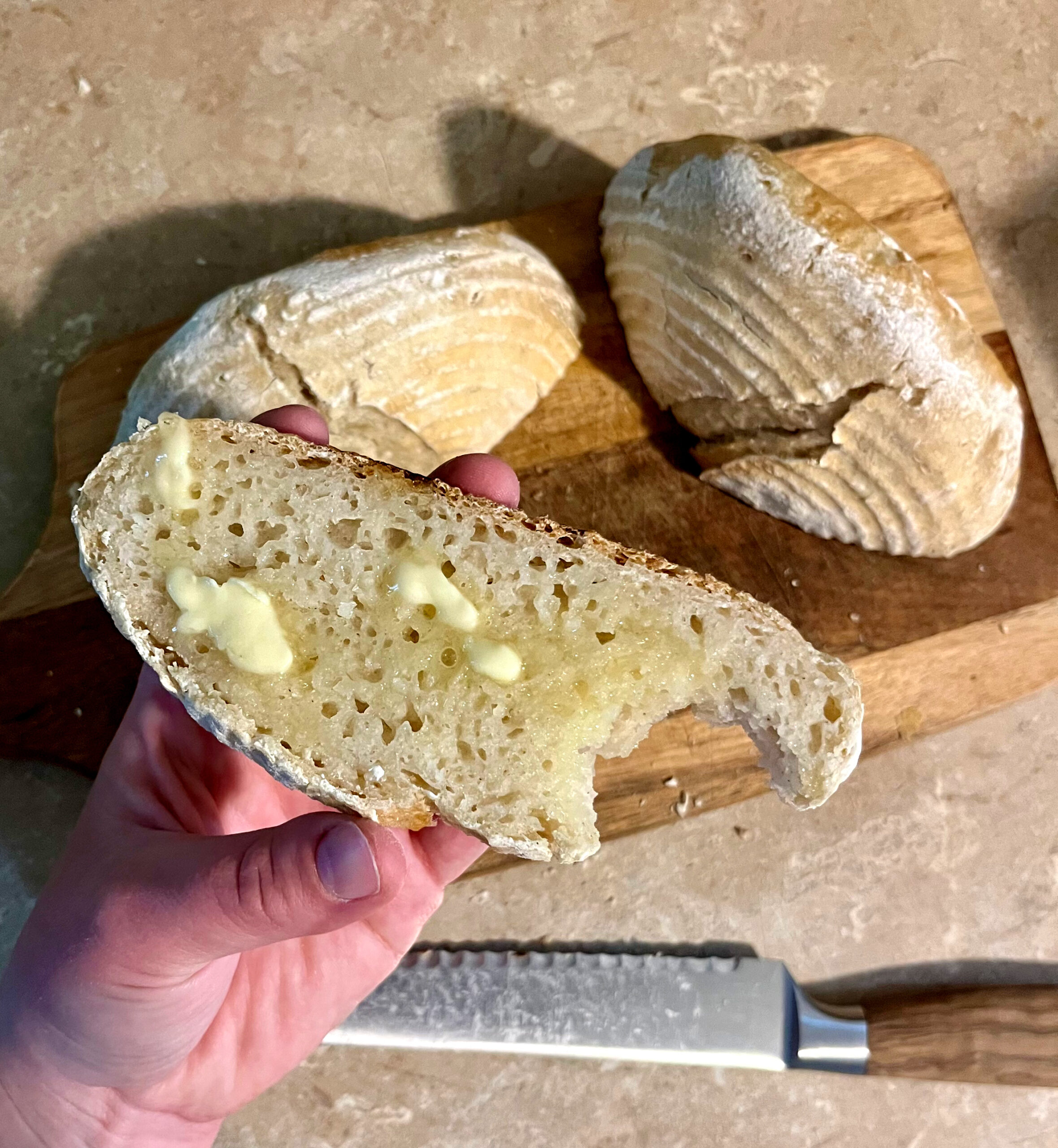 hand holding gluten free sourdough with melted butter on top and a bite taken out of it