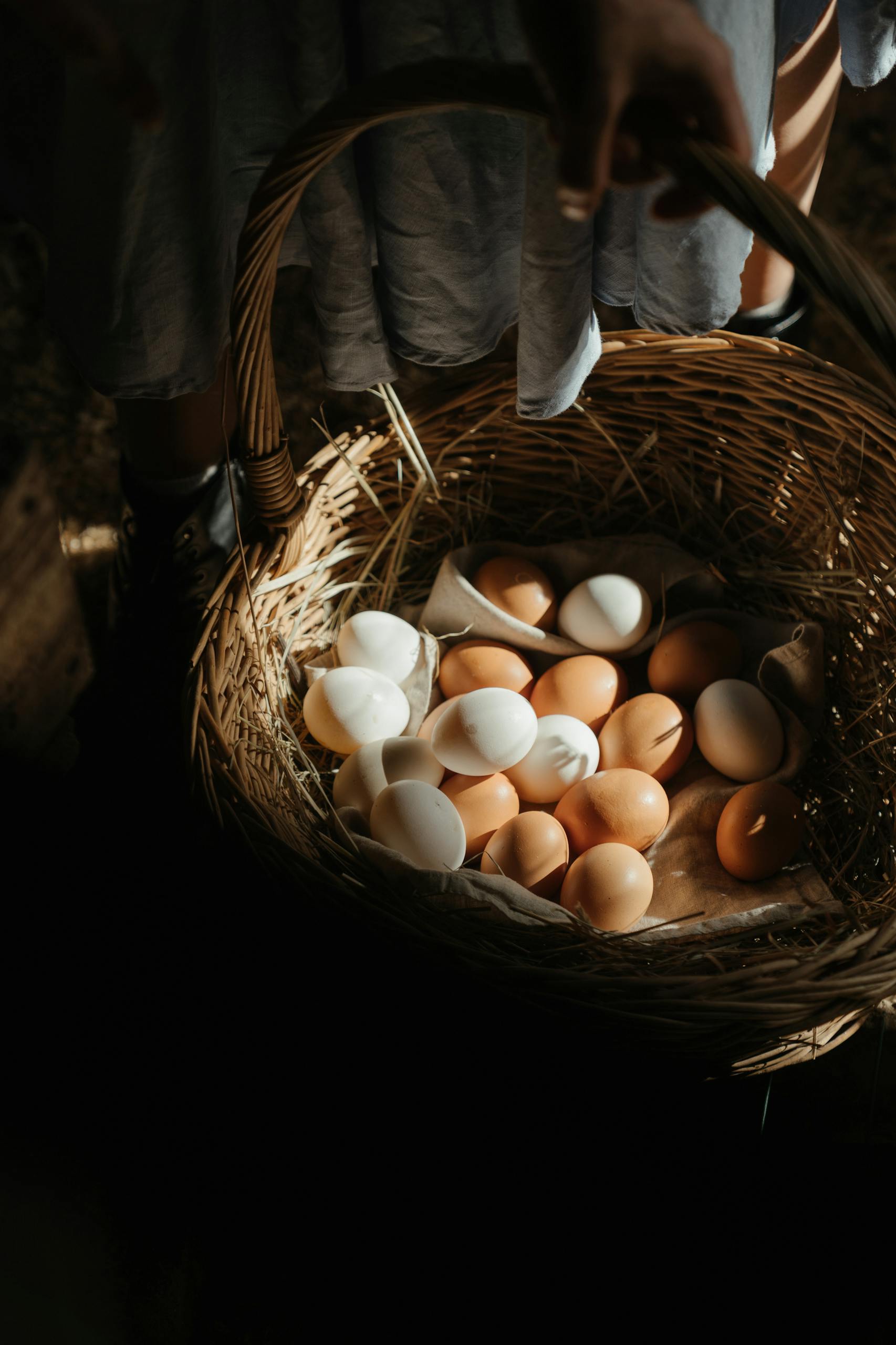 A wicker basket filled with farm fresh eggs in a rural setting.