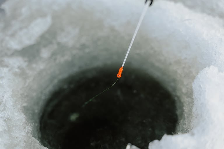 Detailed view of a fishing rod in an icy hole, capturing the essence of winter fishing.
