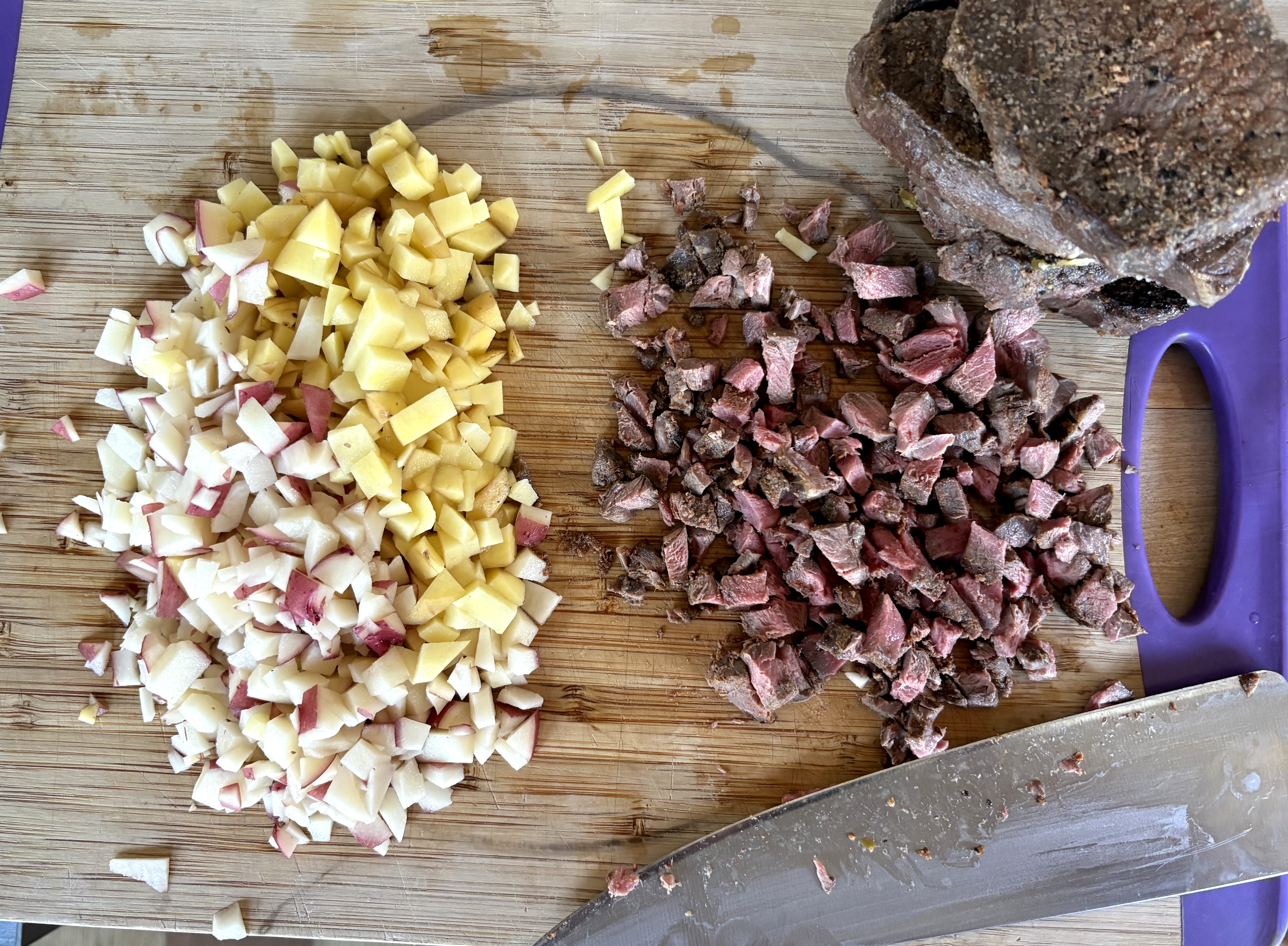 chopped potatoes and chopped venison on a cutting board