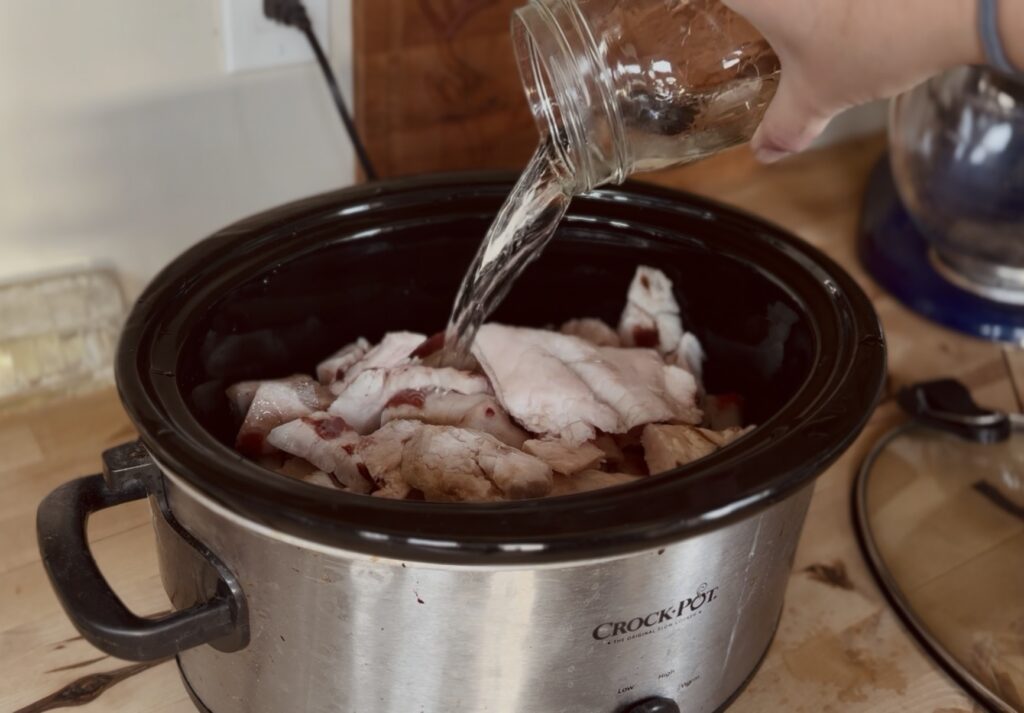 pouring water over deer fat in a crockpot