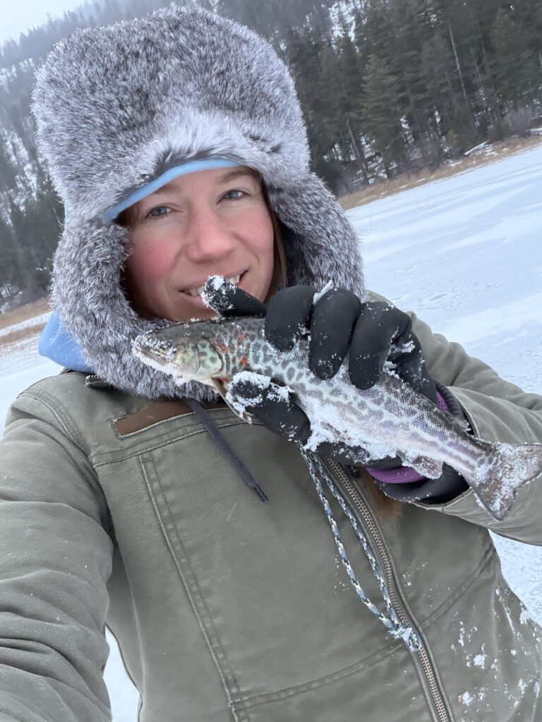 Woman holding tiger trout on frozen lake